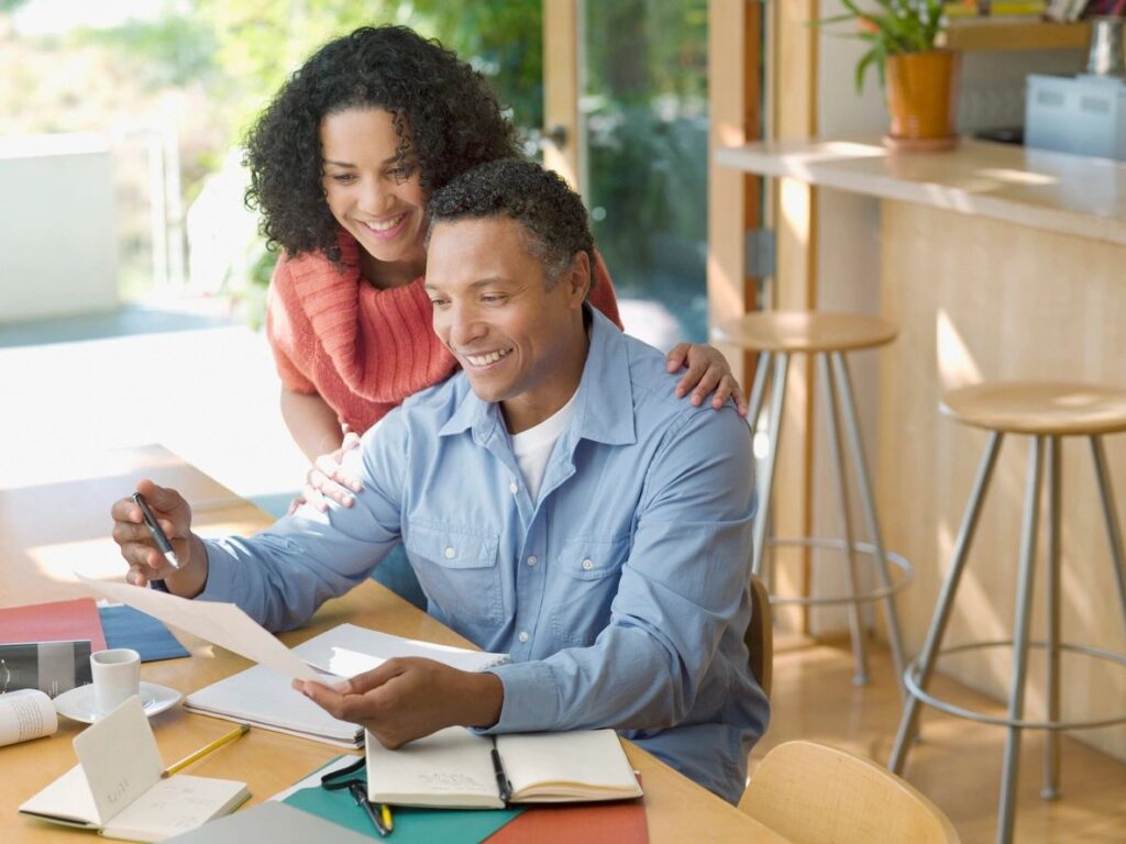 A Man And A Woman Sitting With Papers In Hand