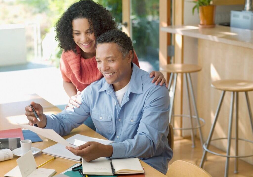 A Man And A Woman Sitting With Papers In Hand